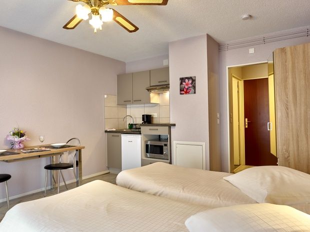 appart-hotel-residence-amneville-chambre-lit-oreiller-cuisine-table-chaise-porte-cadre-fleur
